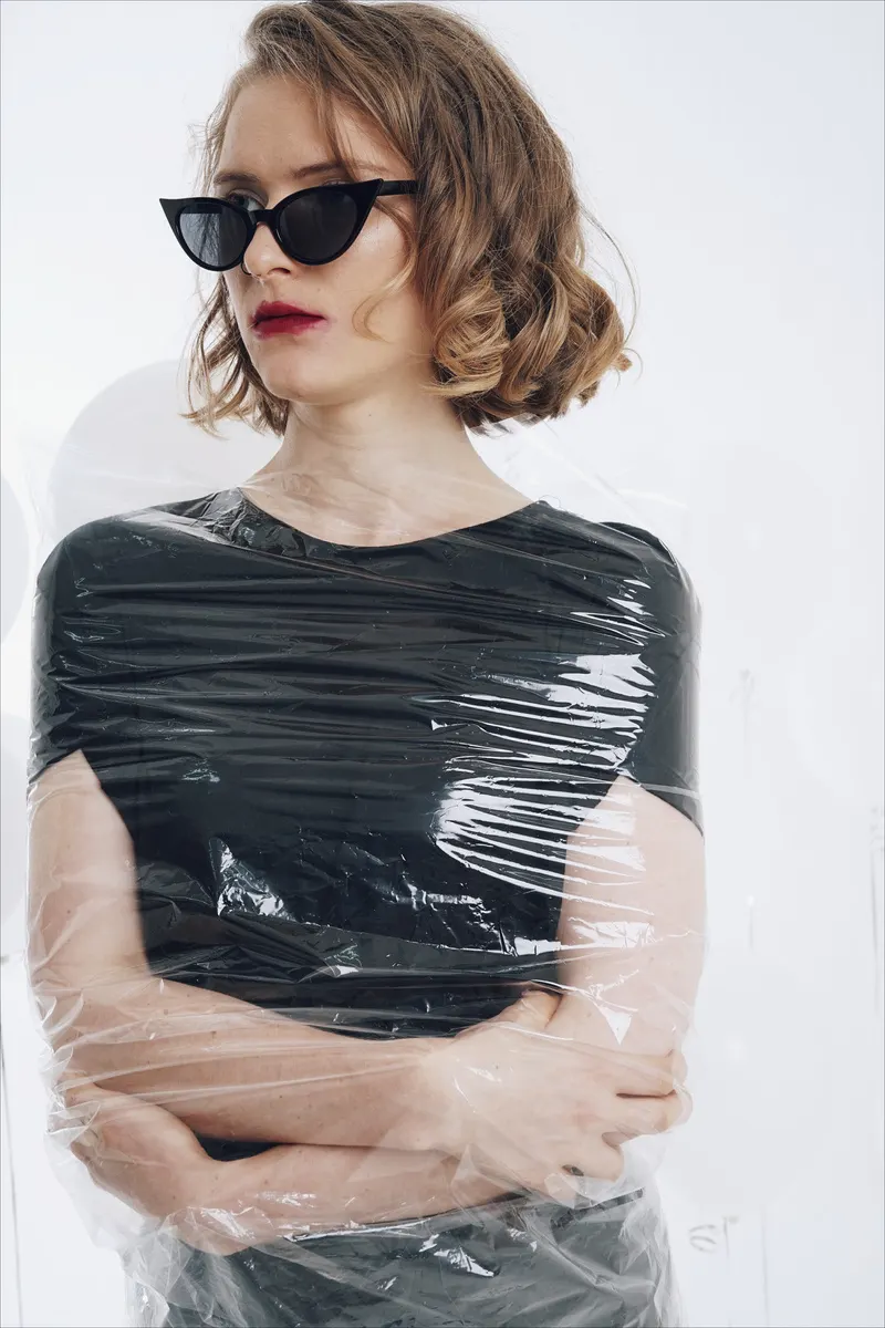 Eva in cat-eye sunglasses, wrapped in cellophane