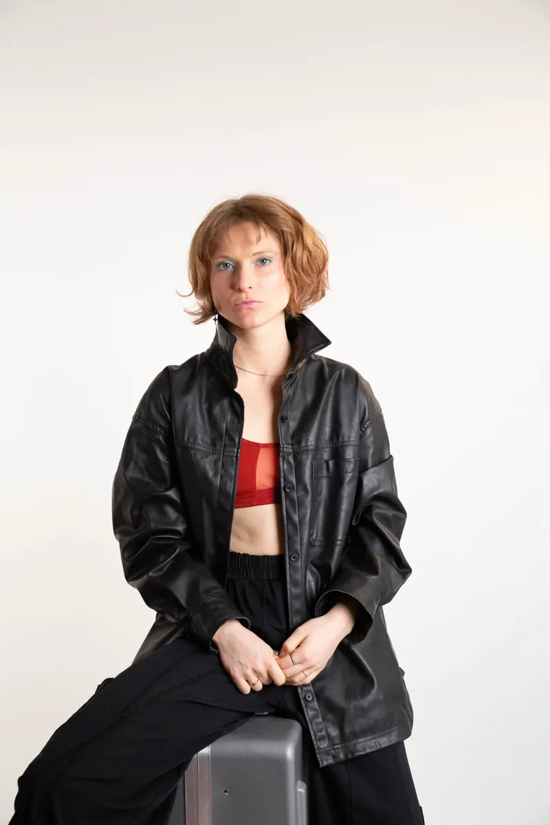 Eva in a black leather jacket, seated on a flight case